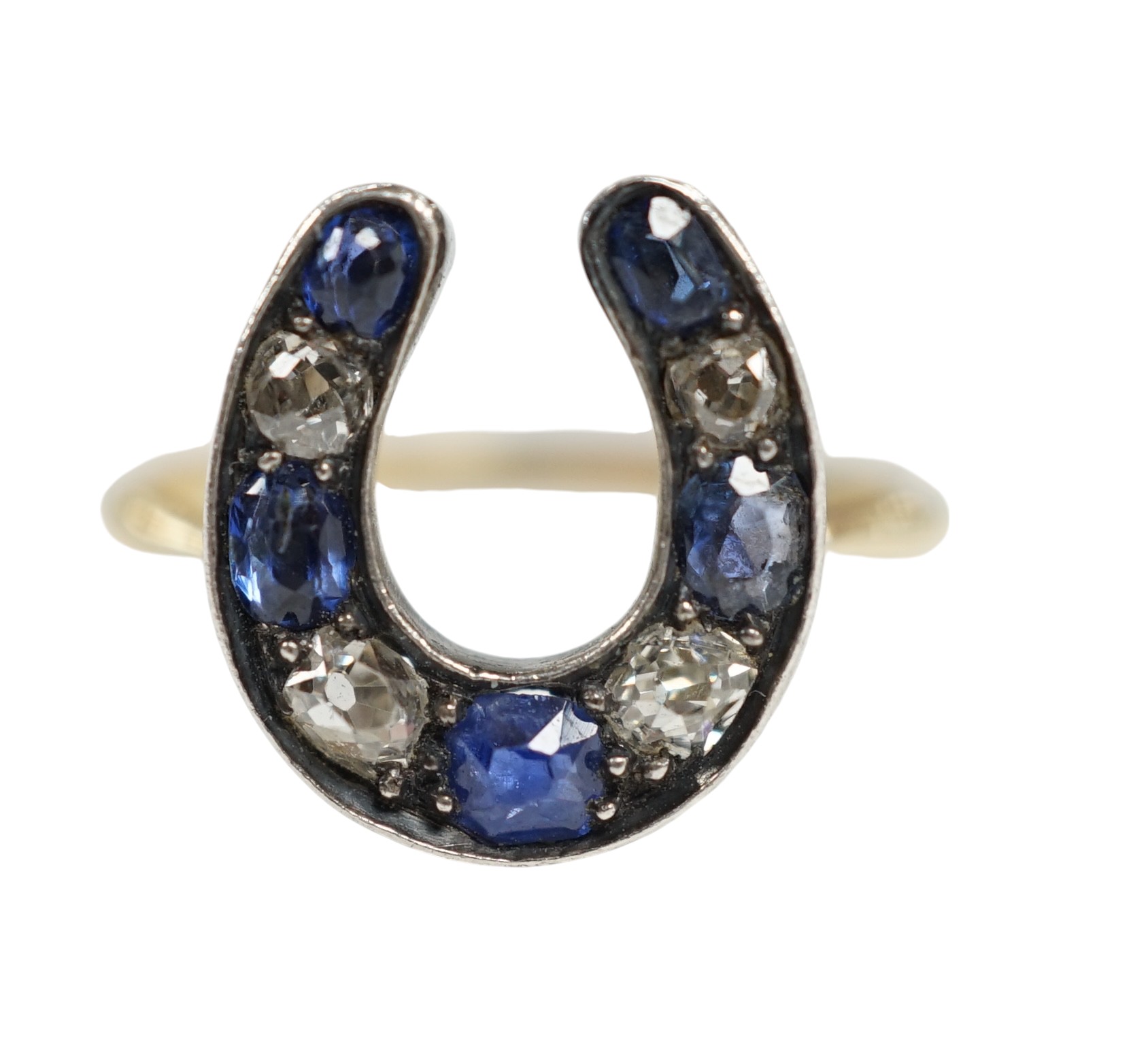 An early 20th century yellow metal (stamped 15), sapphire and diamond cluster set horseshoe shaped ring, size M, gross weight 2.8 grams. Condition - poor to fair